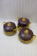 Set of three deep maroon insulated hot pots with gold handles and honeycomb gold accent trim on a kitchen counter.