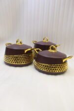 Set of three deep maroon insulated hot pots with gold handles and honeycomb gold accent trim on a kitchen counter.