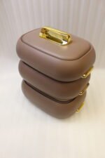 Three stacked matte taupe One More insulated hot pots with gold handles on a white kitchen countertop.