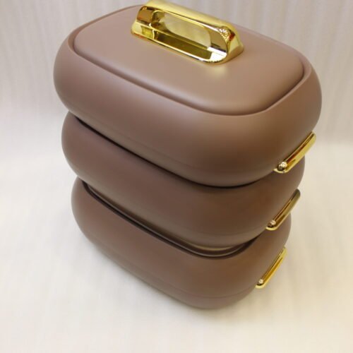 Three stacked matte taupe One More insulated hot pots with gold handles on a white kitchen countertop.