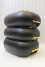 Three matte black insulated hot pot food containers with gold lid handles resting on a marble kitchen countertop.
