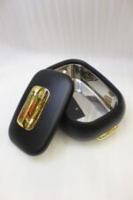 Three matte black insulated hot pot food containers with gold lid handles resting on a marble kitchen countertop.