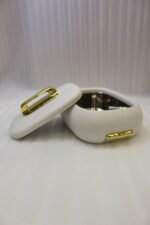 Three stacked off-white insulated hot pot casseroles with metallic gold handles sitting on a marble kitchen countertop.