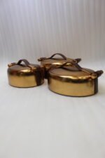 3-piece luxury brushed gold oval insulated hot pot set with leather accent handles displayed on a wooden dining table