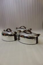 Set of three One More polished stainless steel oval hot pots with brown leather handles in 2L, 2.5L, and 3L sizes on a wooden tabletop.