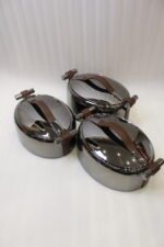 One More 3-piece gunmetal stainless steel insulated hot pot set with wood-grain handles on a wooden table.