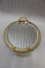 Set of three silver mirrored oval serving trays with floral etchings and textured gold handles on a marble countertop.