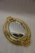 Set of three silver mirrored oval serving trays with floral etchings and textured gold handles on a marble countertop.