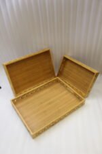 Set of 3 ONEMORE natural wood serving trays with carved geometric side patterns and built-in handles on a marble countertop
