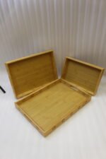 Three-piece natural wooden serving tray set with decorative floral side cutouts displayed on a marble kitchen counter.