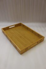 Three-piece natural wooden serving tray set with decorative floral side cutouts displayed on a marble kitchen counter.