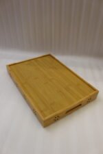 Three-piece natural wooden serving tray set with decorative floral side cutouts displayed on a marble kitchen counter.