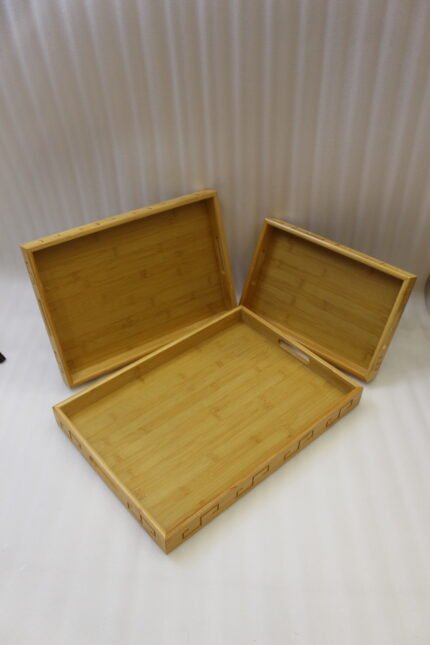 3 piece natural wooden serving tray set with cut-out side handles and engraved geometric border design displayed on a marble kitchen counter