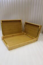 Set of three rectangular natural wood serving trays with gold metal handles displayed on a white marble kitchen countertop.