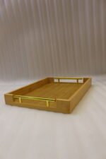 Set of three rectangular natural wood serving trays with gold metal handles displayed on a white marble kitchen countertop.