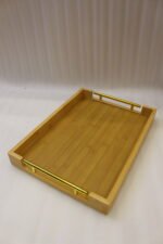 Set of three rectangular natural wood serving trays with gold metal handles displayed on a white marble kitchen countertop.