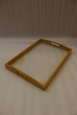 Set of three natural wood nesting serving trays with cutout handles and smooth white inner bases displayed on a kitchen marble countertop.