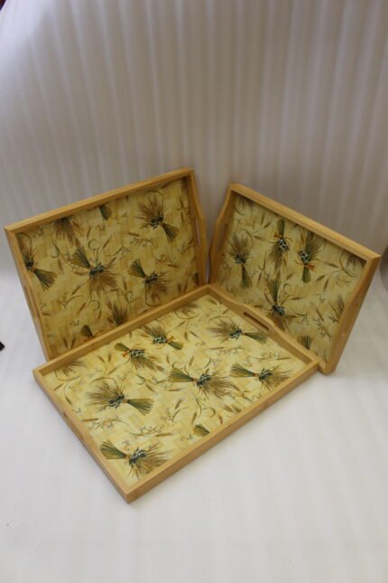 Set of three light wood rectangular serving trays featuring a golden wheat sheath pattern and built-in side handles displayed on a kitchen counter.