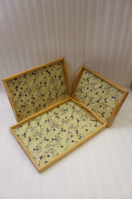 3 piece wooden serving tray set with floral printed base and built in handles on a kitchen countertop