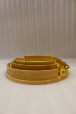 Set of 3 nesting round bamboo wooden serving trays with stylish gold metal handles on a white countertop.
