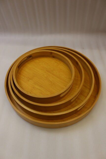 4-piece round wooden nesting serving tray set with built-in cut-out handles stacked on a white kitchen countertop