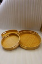 4-piece round wooden nesting serving tray set with built-in cut-out handles stacked on a white kitchen countertop