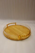 Set of three round wooden nesting serving trays with curved gold handles and clear textured glass rims stacked on a grey marble kitchen countertop.