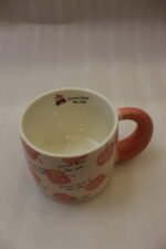 Cream ceramic coffee mug featuring a Snow White apple with a black bow, "Be a princess today" text, and a thick pink rounded handle sitting on a marble kitchen counter.Cream ceramic coffee mug featuring a Snow White apple with a black bow, "Be a princess today" text, and a thick pink rounded handle sitting on a marble kitchen counter.