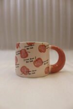 Cream ceramic coffee mug featuring a Snow White apple with a black bow, "Be a princess today" text, and a thick pink rounded handle sitting on a marble kitchen counter.