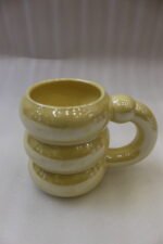 Four iridescent chubby ceramic mugs in pastel pink, yellow, mint green, and white displayed on a marble countertop.