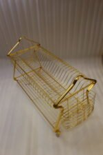 2 tier luxury gold metal dish drying rack with utensil basket, glass holder hooks, and clear drip tray on a kitchen countertop next to a faucet.