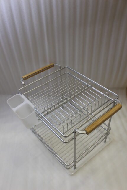 Two-tier silver dish drying rack with wooden side handles, hanging utensil holders, and a plastic drip tray on a kitchen countertop.