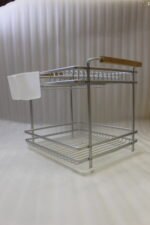 Two-tier silver dish drying rack with wooden side handles, hanging utensil holders, and a plastic drip tray on a kitchen countertop.
