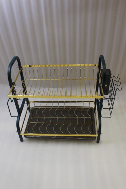 Two-tier gold and black metal dish drying rack with removable drip tray and utensil holder on a white marble kitchen countertop.