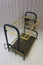 Two-tier gold and black metal dish drying rack with removable drip tray and utensil holder on a white marble kitchen countertop.