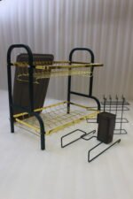 Two-tier gold and black metal dish drying rack with removable drip tray and utensil holder on a white marble kitchen countertop.