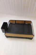 Matte black metal dish drying rack with natural wooden side accents, a black cutlery holder, and a removable drip tray sitting next to a kitchen sink.