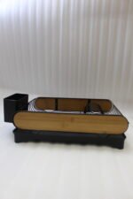 Matte black metal dish drying rack with natural wooden side accents, a black cutlery holder, and a removable drip tray sitting next to a kitchen sink.
