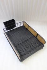 Matte black metal dish drying rack with natural wooden side accents, a black cutlery holder, and a removable drip tray sitting next to a kitchen sink.
