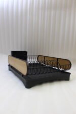 Matte black metal dish drying rack with natural wooden side accents, a black cutlery holder, and a removable drip tray sitting next to a kitchen sink.