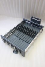 Modern grey and silver expandable kitchen dish drying rack with plate slots, utensil caddy, and drain spout sitting on a countertop next to a sink.