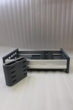 Modern grey and silver expandable kitchen dish drying rack with plate slots, utensil caddy, and drain spout sitting on a countertop next to a sink.