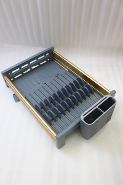 Modern grey and gold dish drying rack placed next to a sink on a kitchen countertop.