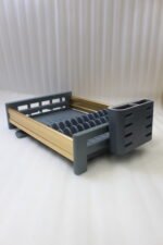 Modern grey and gold dish drying rack placed next to a sink on a kitchen countertop.
