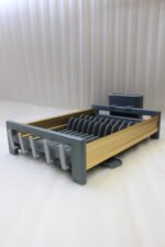 Modern grey and gold dish drying rack placed next to a sink on a kitchen countertop.