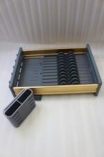 Modern grey and gold dish drying rack placed next to a sink on a kitchen countertop.