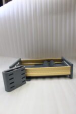 Modern grey and gold dish drying rack placed next to a sink on a kitchen countertop.