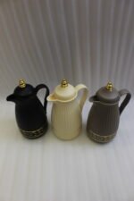 Three ONE MORE 1-liter ribbed luxury vacuum flasks in black, cream, and taupe with gold top finials on a marble kitchen counter.Three ONE MORE 1-liter ribbed luxury vacuum flasks in black, cream, and taupe with gold top finials on a marble kitchen counter.