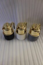 Three One More 1 liter luxury thermal vacuum flasks in black, white, and grey with polished gold tops on a marble kitchen countertop.