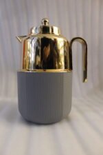 Three One More 1 liter luxury thermal vacuum flasks in black, white, and grey with polished gold tops on a marble kitchen countertop.